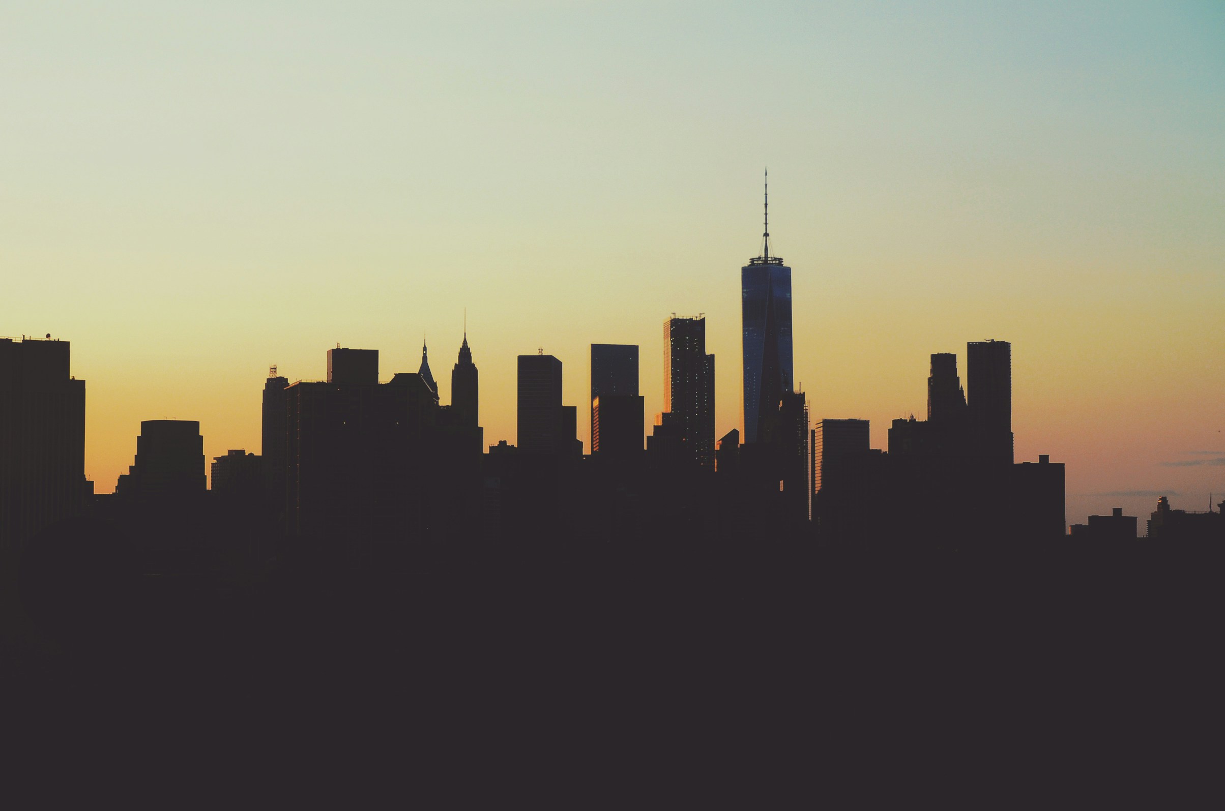 The Lower Manhattan skyline in silhouette against a dusk sky